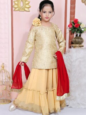 Nikhaar Creations Gold Brocade Short Lehenga Choli Kurti Cold Shouldered Full Sleeves With Gold Polka Dot Shimmer Georgette 2 Tiered Ghagra Having Kundan Stones Embroidered Border On Its Hemline With A Shimmer Floral Motif On Shoulder Worn With A Red Georgette Dupatta With Gold Fringes On Two Small Edges.